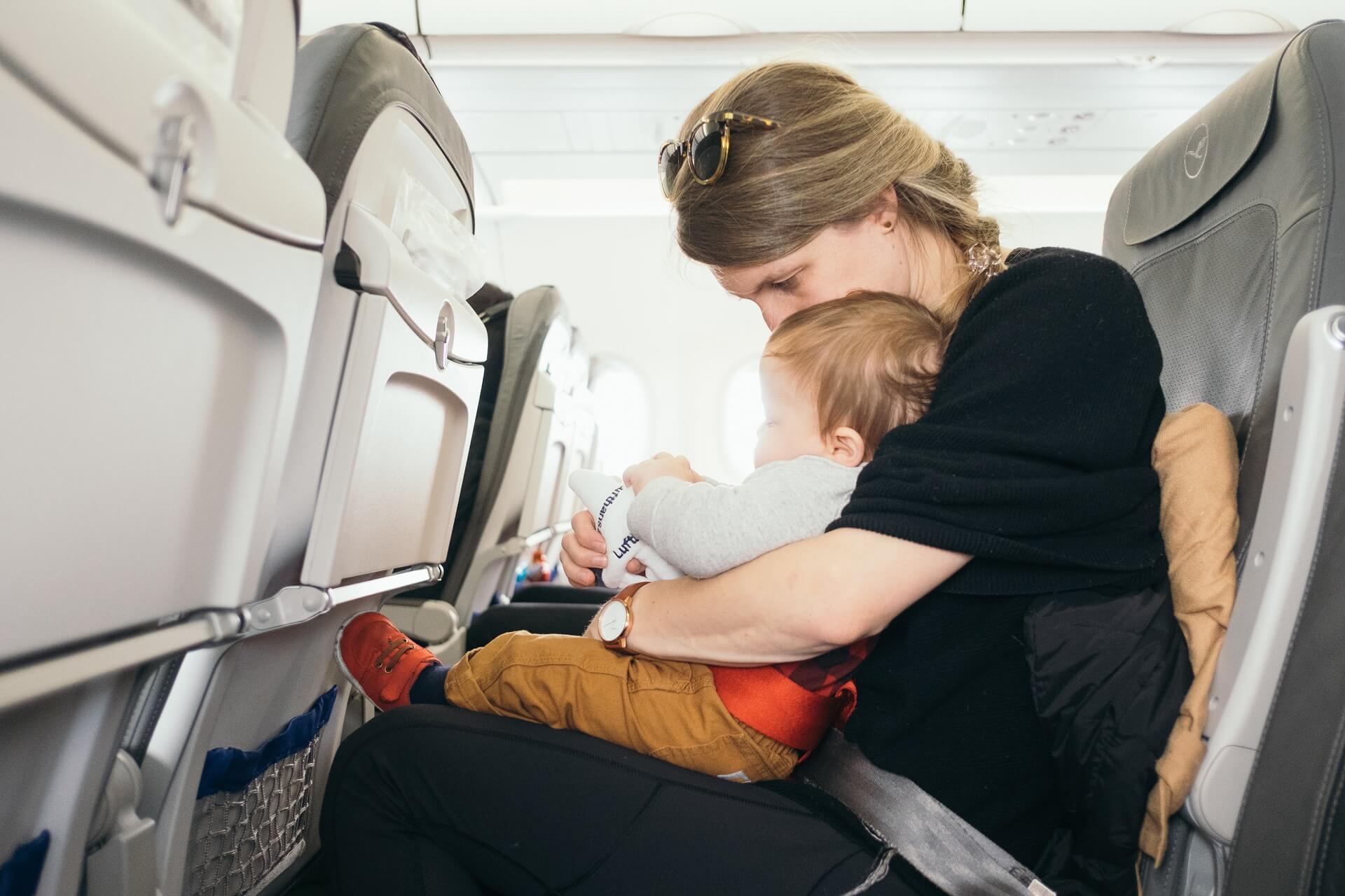 Mutter im Flugzeug mit Baby auf dem Schoß