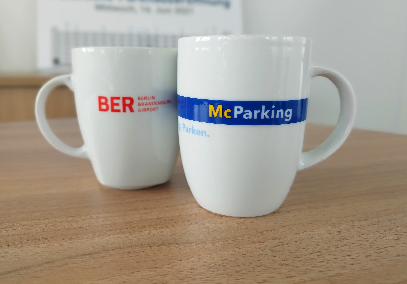 2 Tassen eine mit BER Logo und eine mit McParking Logo