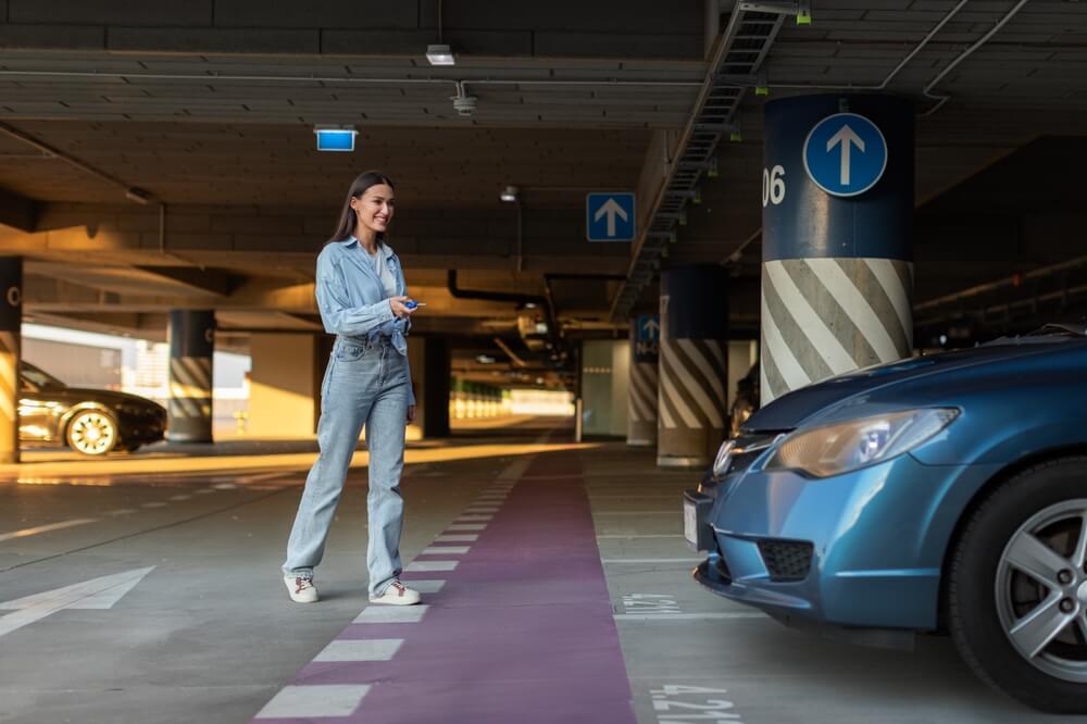 Günstig und bequem am BER parken - Frau geht zu Ihrem Parkplatz im Parkhaus BER parken - Eine Frau geht im Parkhaus mit dem Autoschlüssel in der Hand auf ihr Auto zu